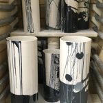 Vases cylindriques dans le four. Décors d'engobes noir, blanc et gris.